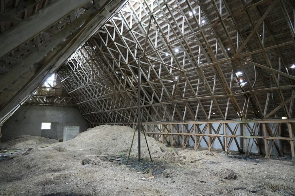 A homeowner examines continuous attic insulation and ventilation channels beneath a sloped residential roof.
