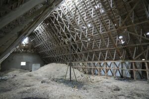 A homeowner examines continuous attic insulation and ventilation channels beneath a sloped residential roof.